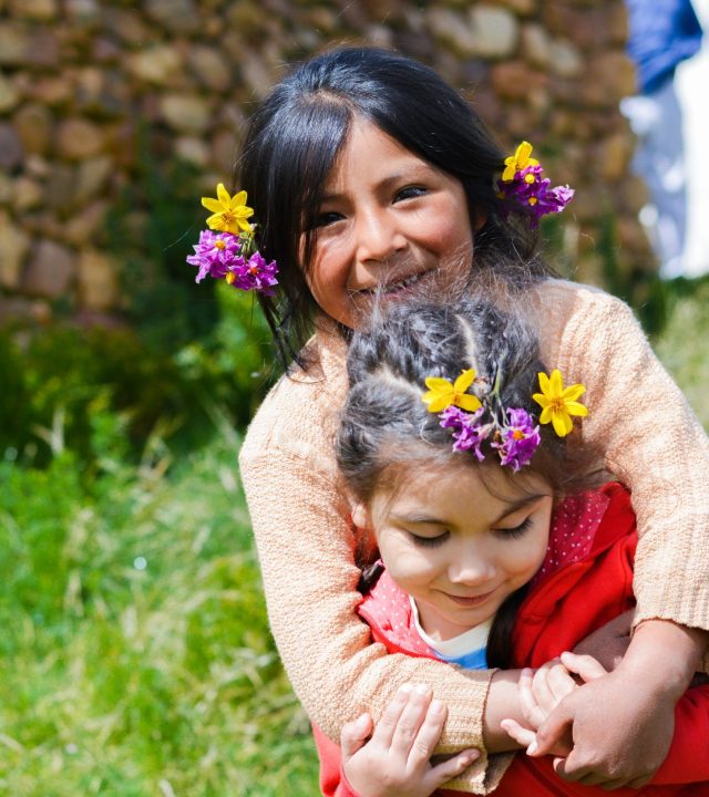 Two little latin girls hugging outside.